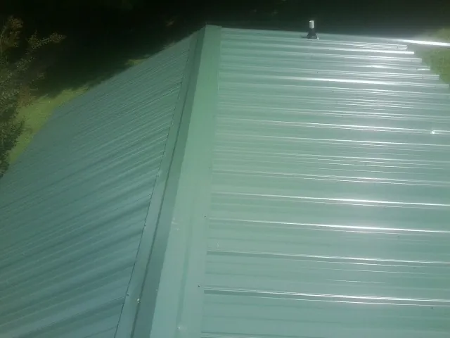 New green metal panels meeting at the ridge of a roof — Flat Roof Repair work by our crew in Plain