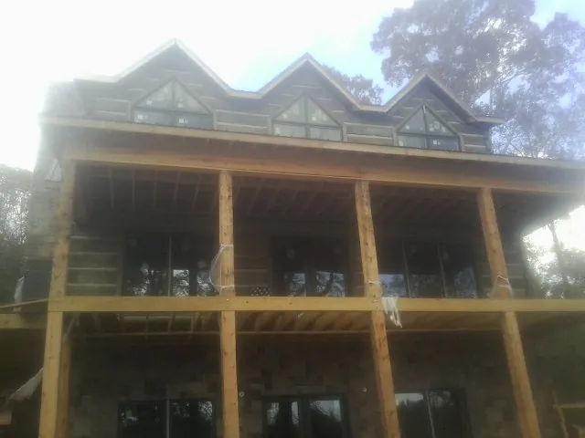 Dormers and porch framing on a large log home under construction — Roof Coating work by our crew in Plain