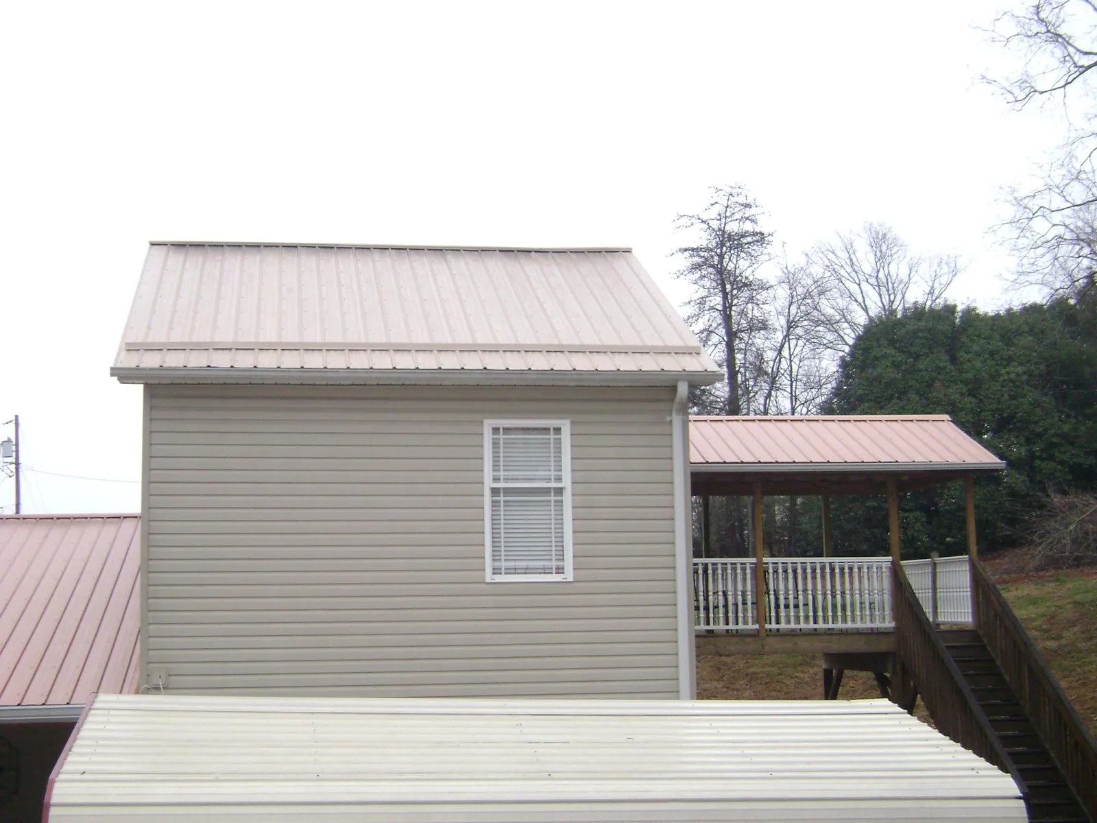 Tan metal roofs on a two story addition and attached porch, from a Roof Replacement job in Plain