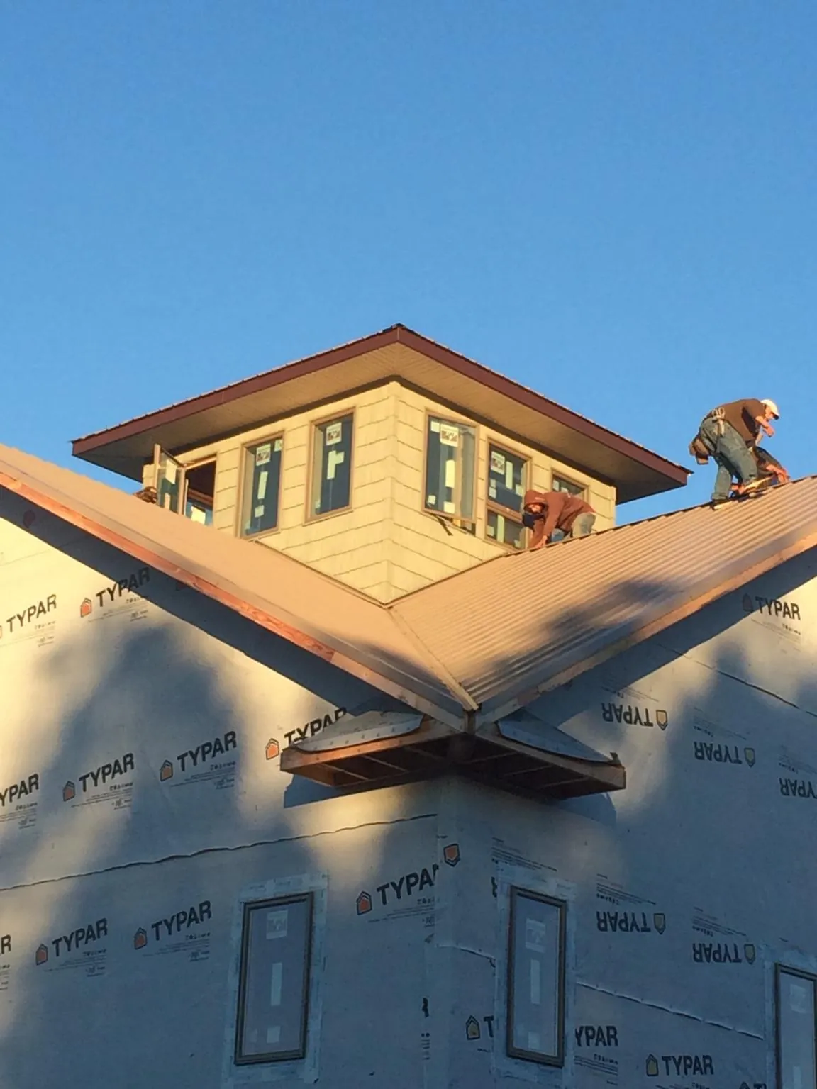 Roofers working around a rooftop cupola on a new metal roof at sunset — Roof Waterproofing in Plain by Roofing Brothers